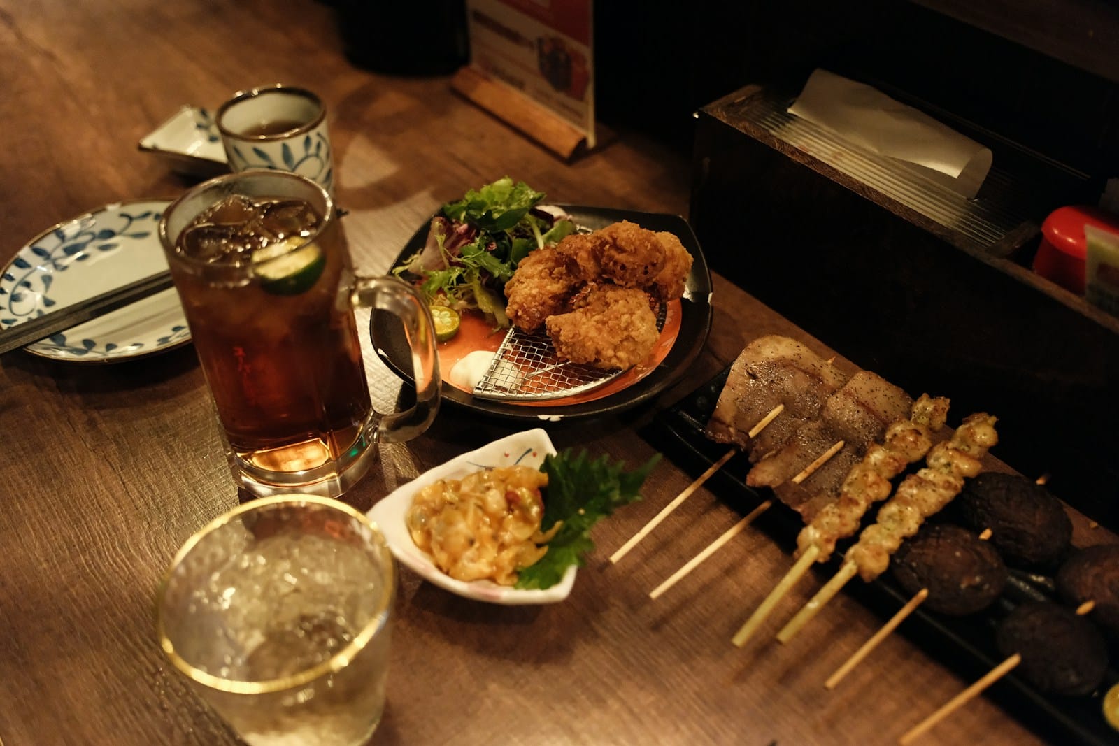 焼き鳥の串と唐揚げ、飲み物が並んだテーブル