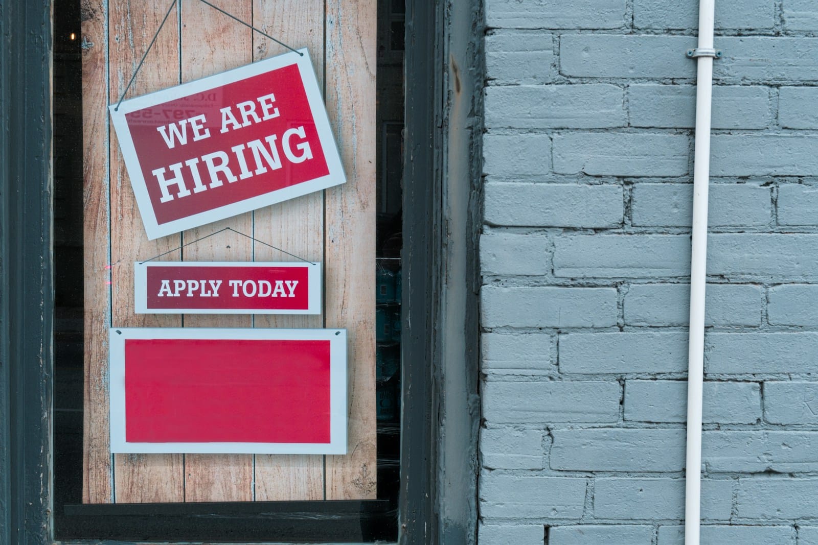 窓に掛けられた「WE ARE HIRING」「APPLY TODAY」の札