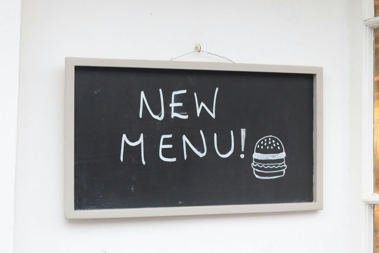 白い壁に掛けられた「NEW MENU!」と書かれた黒板