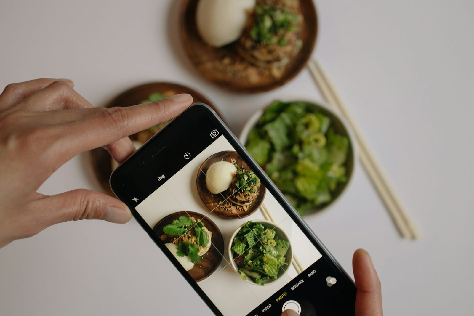 スマートフォンで料理の写真を撮っている手元