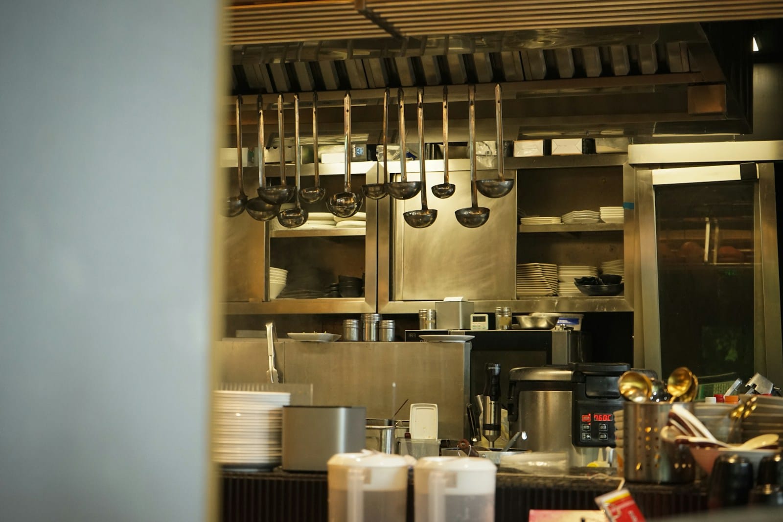 お店の厨房に、おたまや調理道具がずらりと掛けられている