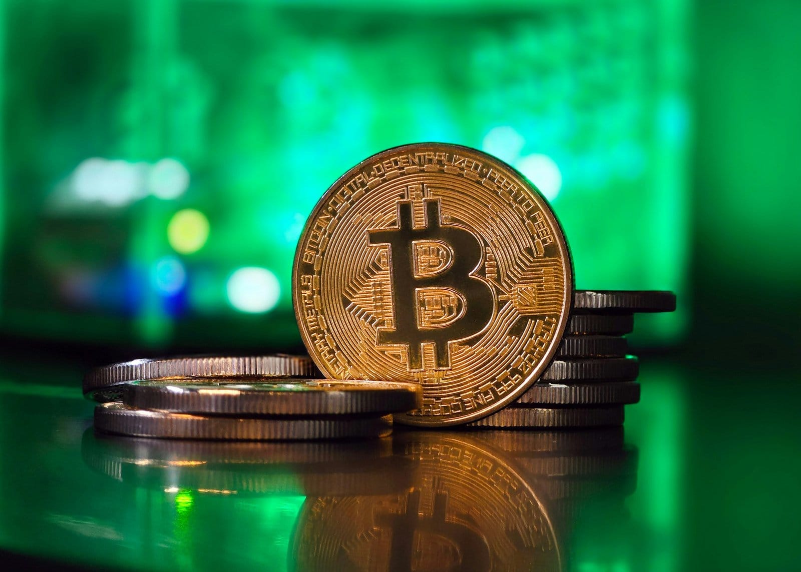 緑の光の前に置かれた金色のビットコインとコインの山