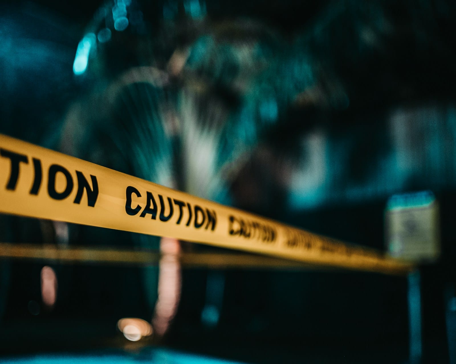 暗い街なかに張られた、「CAUTION」と書かれた黄色い規制テープ