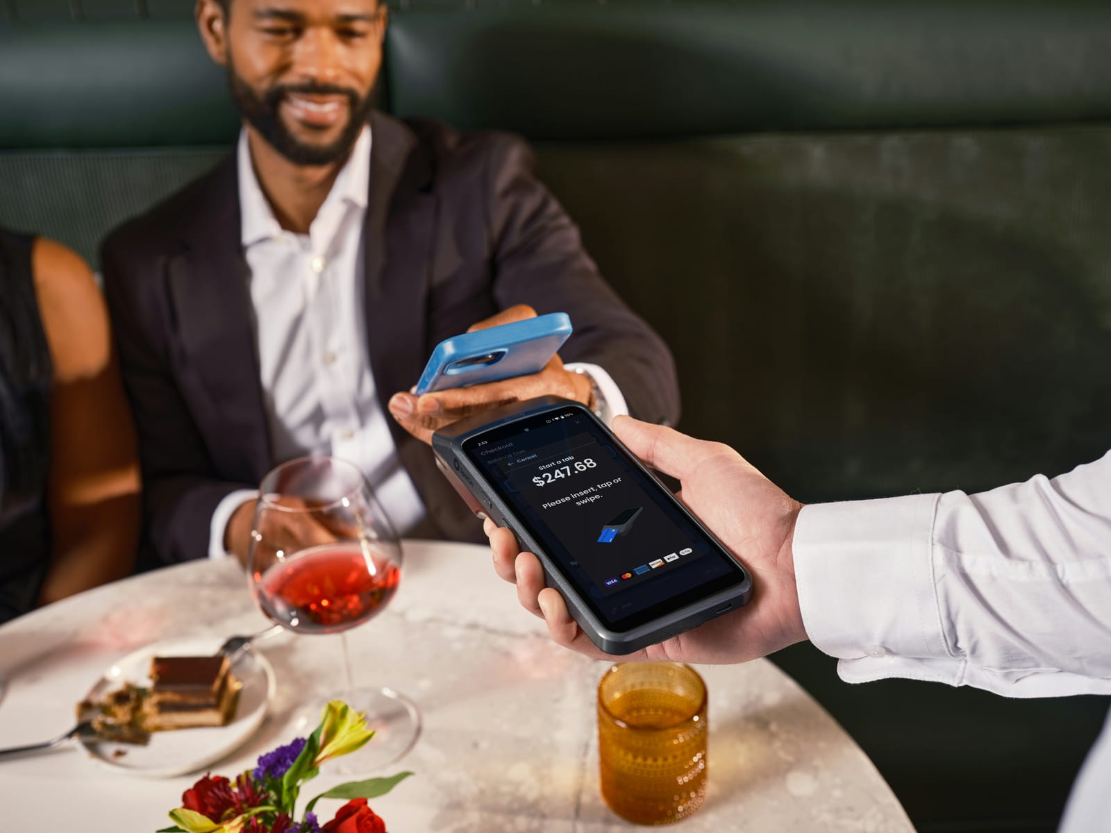 お店でスマートフォンを使って支払いをしている場面